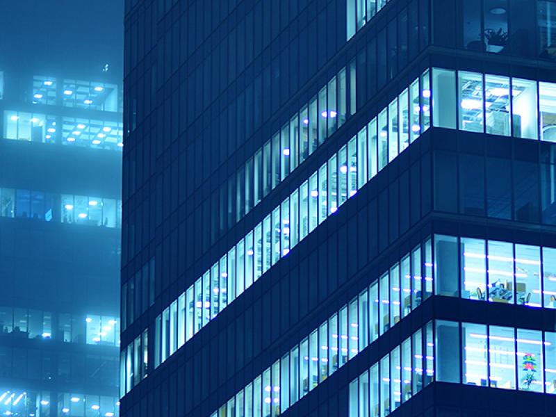 The side of a glass building with some lights on